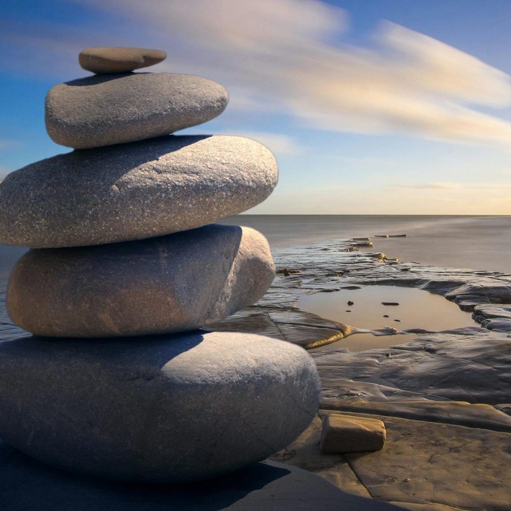 Tower of smooth round beach stones stacked on the seashore with horizon view