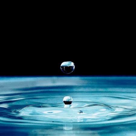 Water droplet rippling into merging concentric circle